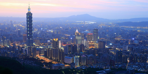 Aerial panorama of busy Taipei City at dusk, with a view of Taipei buildings in downtown area and Tamsui River and distant mountains in the background ~ A Blue and Gloomy evening scenery of Taipei