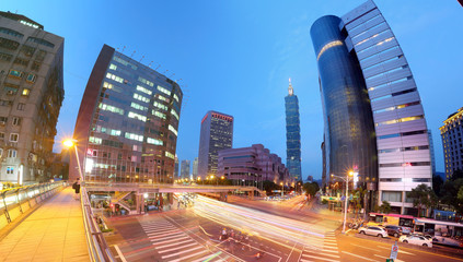 Fototapeta na wymiar Panoramic view of a street corner in Downtown Taipei City with busy traffic trails at rush hour ~ Beautiful night scenery of Taipei 101 Tower & landmark buildings in XinYi Financial District