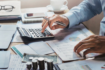 businessman working on desk in office with using calculator for calculate accounting report. finance concept