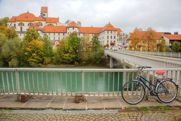 A bicycle parking by Lech River with the majestic Hohes Schloss Castle in the background on a brisk...