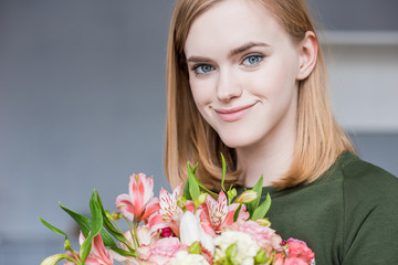 portrait of young smiling woman holding bouquet of flowers