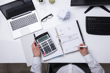 Fototapeta na wymiar High Angle View Of A Businessperson Calculating Bill