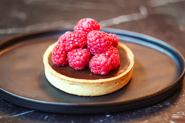 Chocolate raspberry fresh bread bake cup cake serve in black circle dish on wood table with blur background