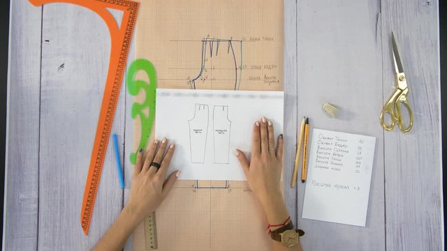 Female hands show a pattern for sewing trousers