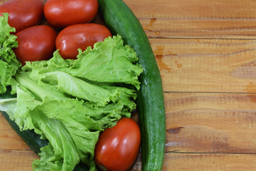 fresh juicy red tomatoes, cucumbers and lettuce on a wooden table