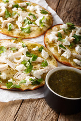 Mexican fast food Chalupas with fresh cheese and chicken meat and green sauce close-up. vertical