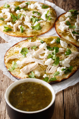 Mexican Chalupas with cheese and chicken meat and sauce salsa verde closeup vertical 