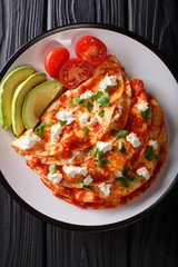 entomatadas with farm cheese and tomato sauce close-up on a plate. Vertical top view