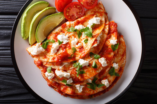 entomatadas with farm cheese and tomato sauce close-up on a plate. Horizontal top view