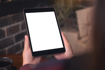 Mockup image of a woman holding black tablet pc with blank white desktop screen in cafe