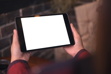 Mockup image of a woman holding black tablet pc with blank white desktop screen in cafe