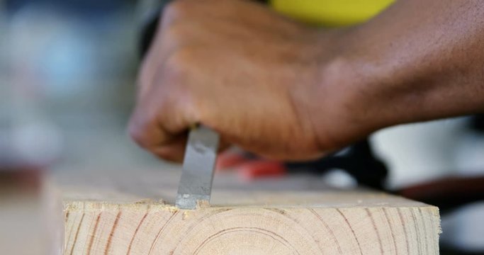 Carpenter carving wood with hammer at table