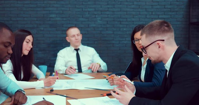 Confident and attractive business group of mixed age and ethnicity meets in a modern start-up room discusses various ideas for implementing a business plan