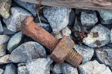big rusted screw on rocky ground texture background