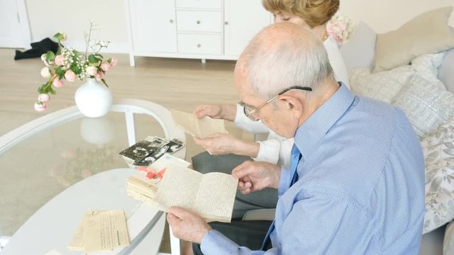 Elderly happy couple spending time together reading old letters