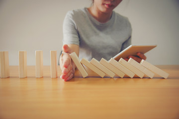Businesswoman Hand Stopping Dominoes From Falling On Office Desk. Risk Prevention Concept
