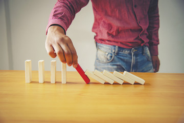 Businessman Hand Stopping Dominoes From Falling On Office Desk. Risk Prevention Concept