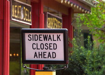 Fototapeta premium Sidewalk closed sign in front of a deli in Northern California. Rural town.