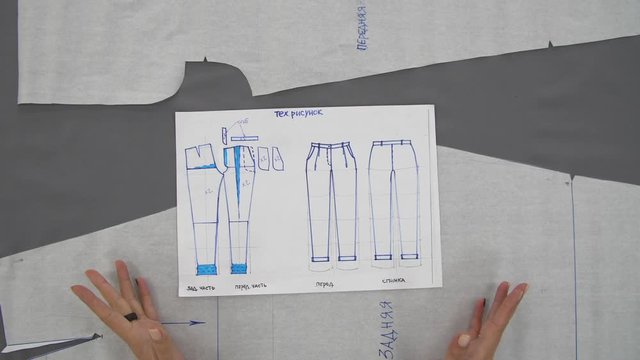 Female hands draw a blue ink scheme for sewing trousers