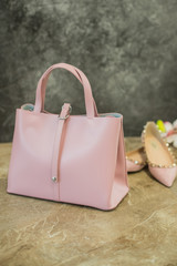 Pair of beige nude women's shoes with handbag on a marble background, flat lay, fashion concept.Set...