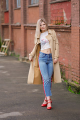 Obraz premium Pretty girl in short jeans and raincoat walking on the street after the rain