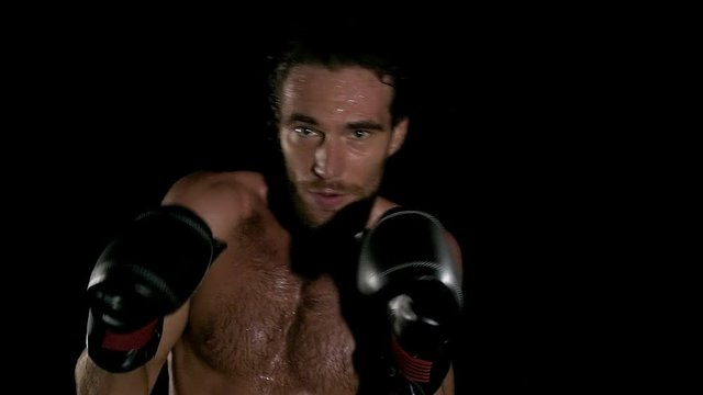 Slow motion of man shadow boxing in black background. Young white man with six packs.. Fighting sprit concept.