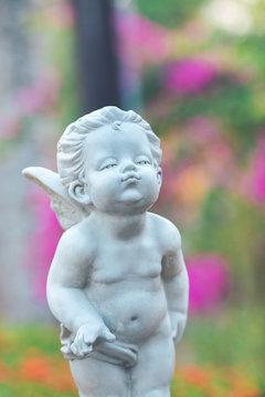 Cupid stone statue in the flower garden.