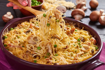 woman's hand is holding a fork with portion of Tetrazzini