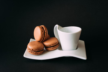 Set of cup of coffee and macaroons against black background