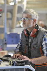 Woodwork technician programming sawmill machine - obrazy, fototapety, plakaty