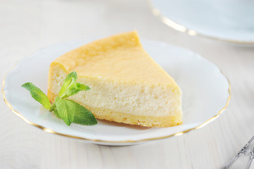 cheesecake and a mint leaf on the saucer with a Golden rim