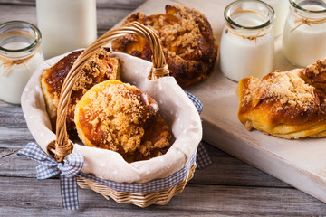 Bread buns in a wicker basket, jars with milk on a cutting board 