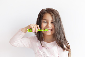 Little cute child girl brushing her teeth on white background. Space for text. Healthy teeth.