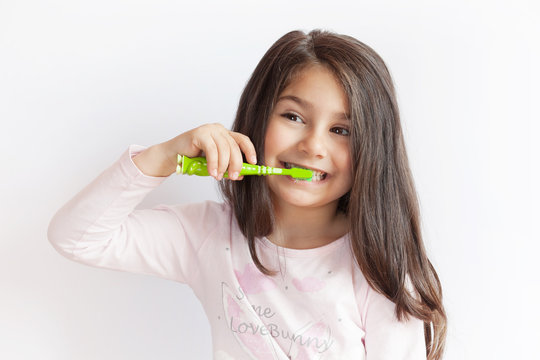 Little cute child girl brushing her teeth on white background. Space for text. Healthy teeth.