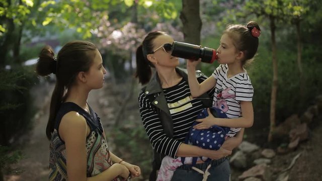 Family vacation. Mother with two daughters, strolling through the Park. Stop to quench their thirst.