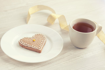 Love consept.  Valentines day. Gingerbread in the shape of heart, a cup of tea, decorative hearts on a wooden table 