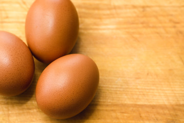 Three brown chicken eggs on a wooden surface background
