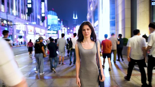 Young attractive woman standing in the crowded street in the center of Shanghai, time lapse video with smashed people in the crowd