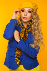fashion photo. blonde in a yellow beret in a blue jacket and yellow pants posing