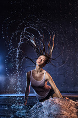 Girl with long hair during photoshoot with water in photo studio
