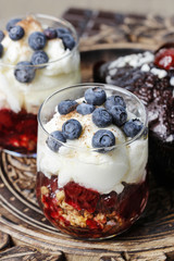 Layer strawberry, blueberry and muesli dessert in transparent glass goblet.