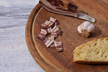 Delicious plate with smoked bacon, garlic and bread at rustic wooden background/ Traditional Balkan food