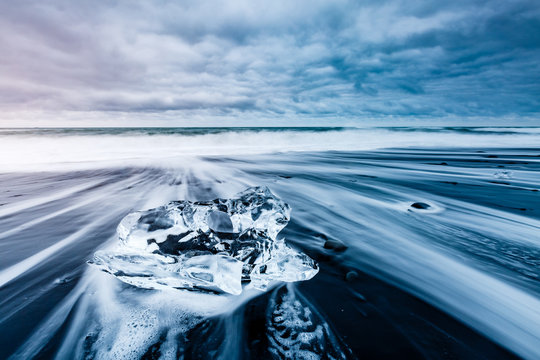 Large pieces of the iceberg that sparkle on the black sand. Location place Jokulsarlon, Vatnajokull national park, Iceland.