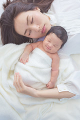 happy mother with baby in bed