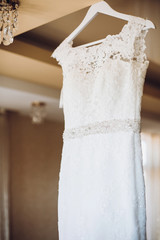 beautiful lace wedding dress on white wooden hanger in provence room in the morning sunlight. space for text. wedding concept