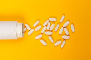 White medical pills on color background