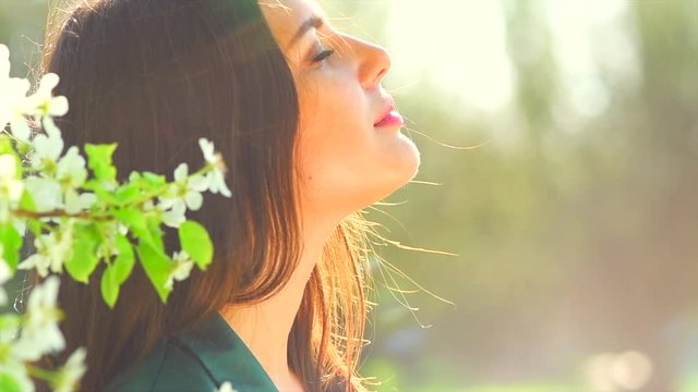 Beauty young woman enjoying nature in spring apple orchard, Happy beautiful girl in garden with blooming trees. Slow motion 4K UHD video footage. 3840X2160
