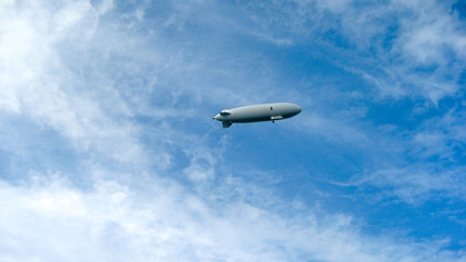 Naklejka na ściany i meble Zeppelin in front of blue sky, some clouds with airship