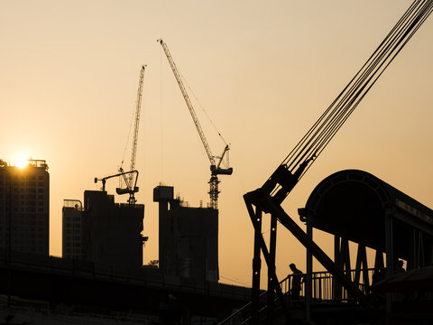 Cranes working on Building Construction site sunset sky Silhouette Industrial background
