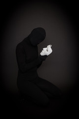 Who am I? Mysterious woman dressed in black holding a white mask